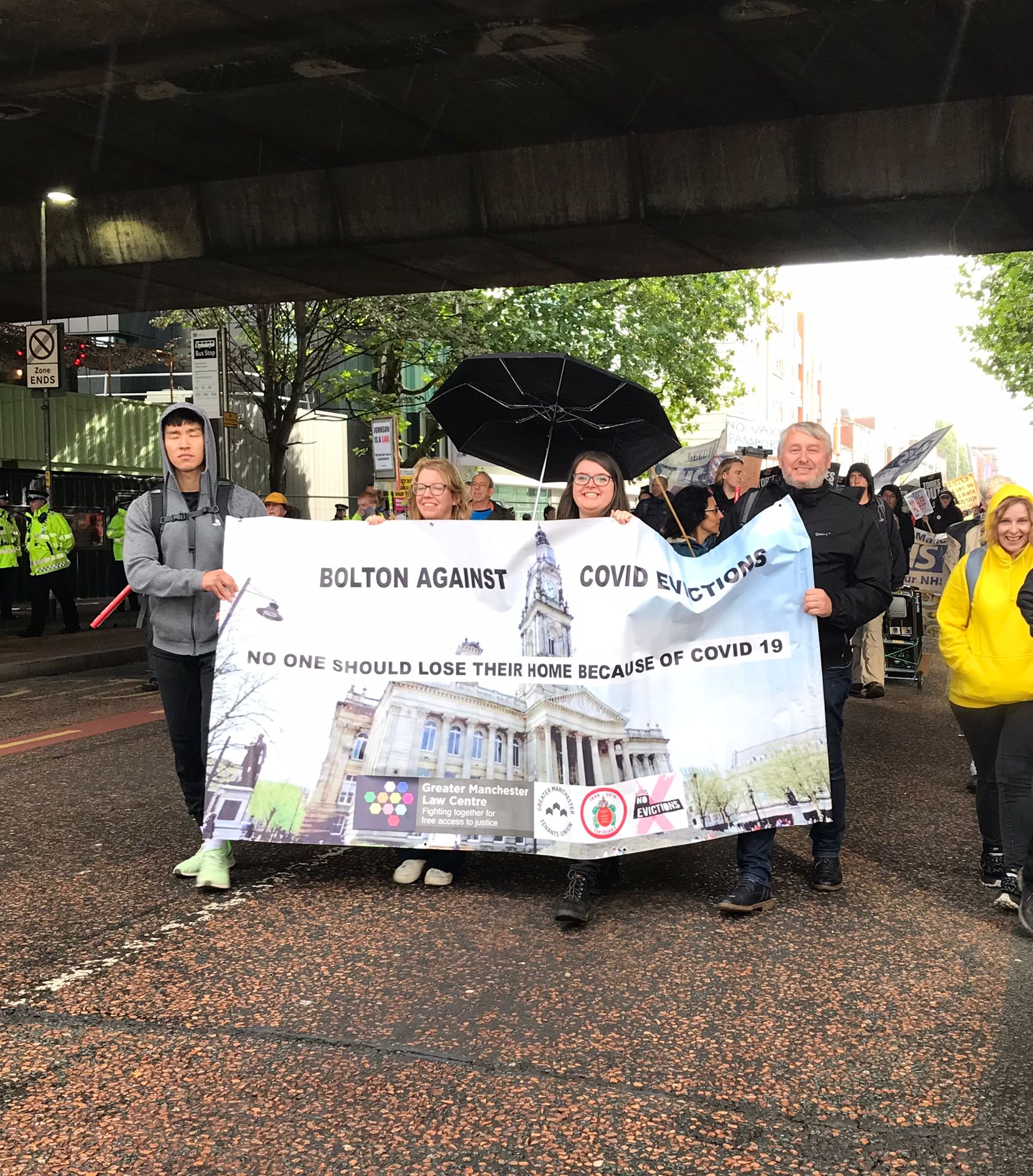 Image shows GMLC team members and volunteers holding a banner reading 'Bolton against Covid evictions'