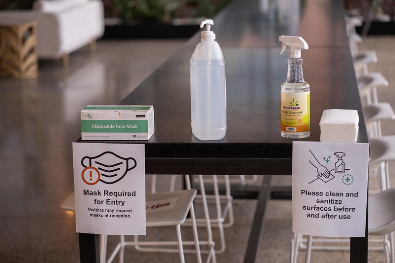 Image shows a set of items on a table for Covid safety in a workplace: disinfectant, masks and hand sanitiser.